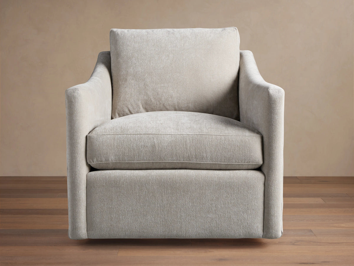 Branson Swivel Chair in beige fabric, features plush seat and back cushions, flared arms, on hardwood floor, against tan background.