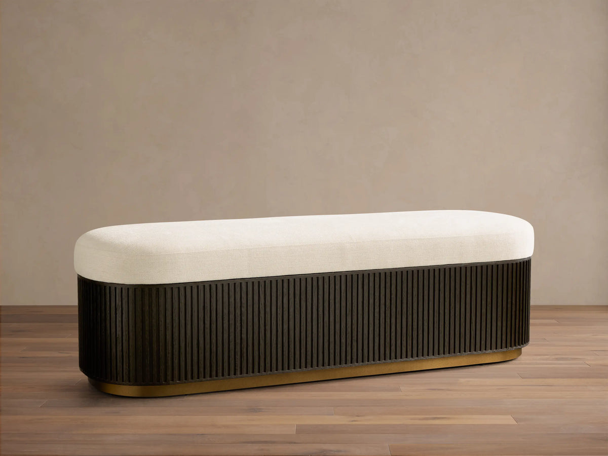 Front view of the cream-cushioned Finnley Storage Bench with a fluted black base and gold trim.