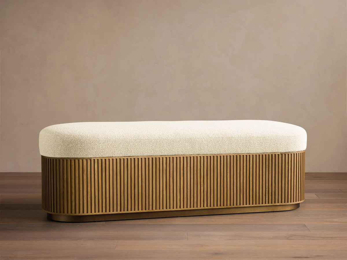 Front view of the Finnley Storage Bench with a cream upholstered top and a honey oak fluted base.