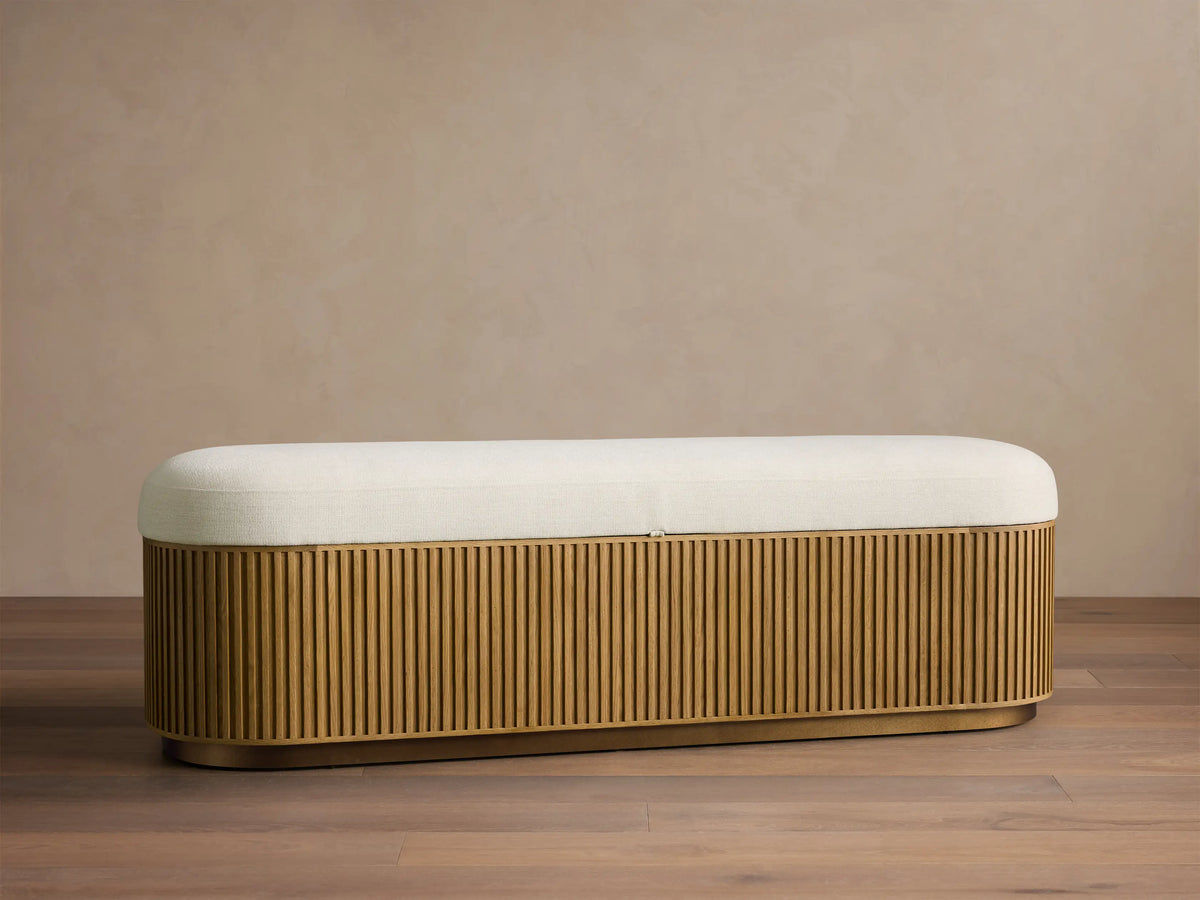 Front view of the Finnley Storage Bench with a light cream upholstered top and a honey-finished slatted wood base.