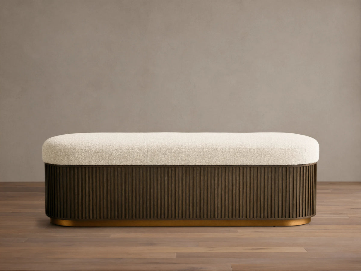 Front view of the Finnley Storage Bench, with a cream textured cushion, dark brown fluted wood base, and gold trim.