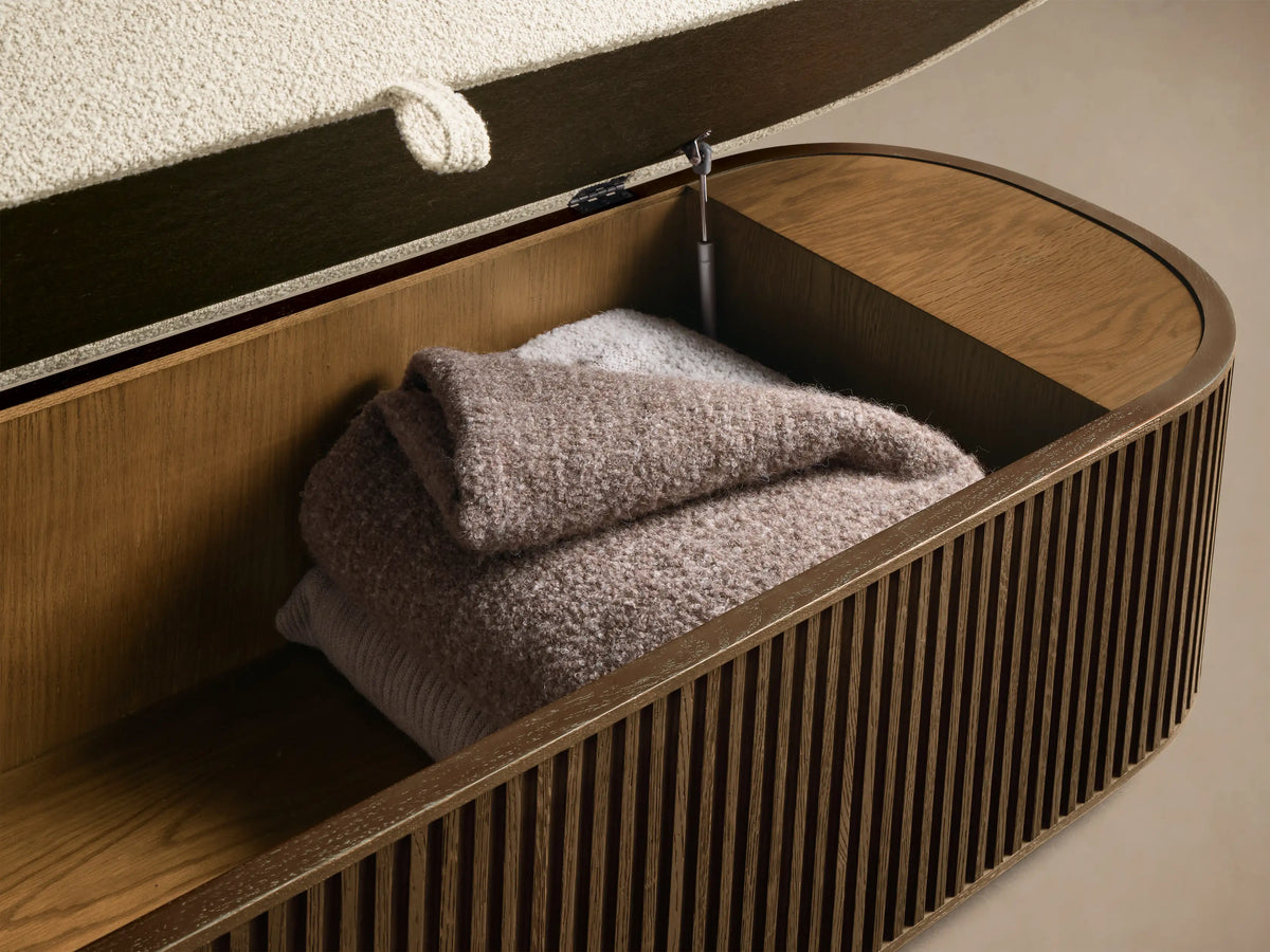 Interior view of the open Mocha Finnley Storage Bench in slatted red oak, holding folded taupe blankets, with a cream cushion lid.