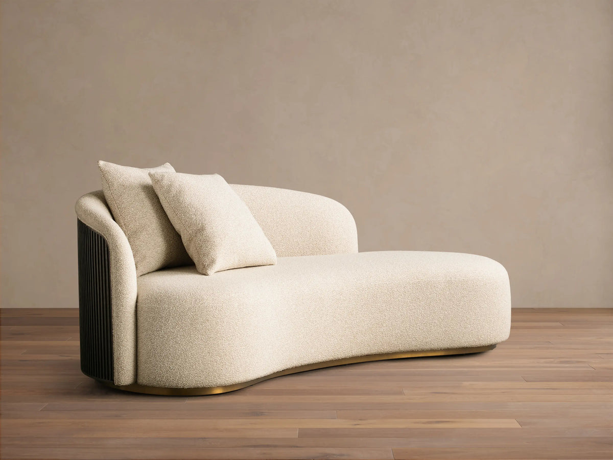 Front view of the cream boucle Finnley Daybed, with two pillows, dark fluted side panel, and gold curved base.