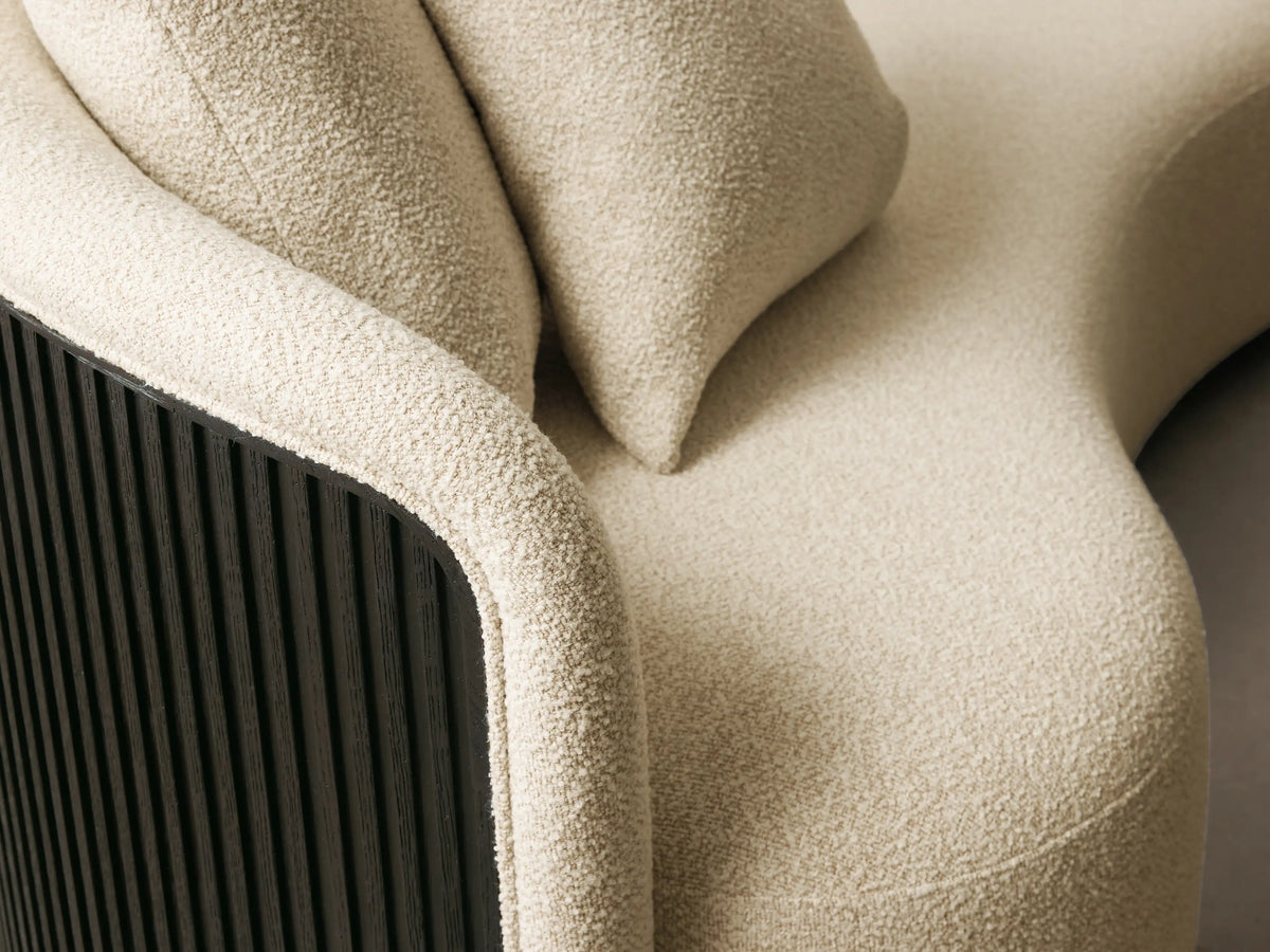 Close-up of the cream bouclv© fabric upholstery and dark ribbed wood frame of the Finnley Daybed.
