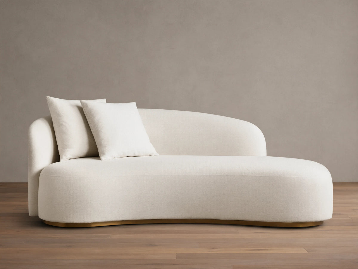 Front view of the cream Finnley Daybed, featuring a curved upholstered design, two matching toss pillows, and a gold-toned base.