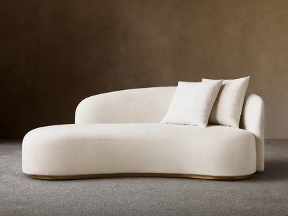 Front view of the cream Finnley Daybed, featuring a curved upholstered design, two matching toss pillows, and a gold-toned base.