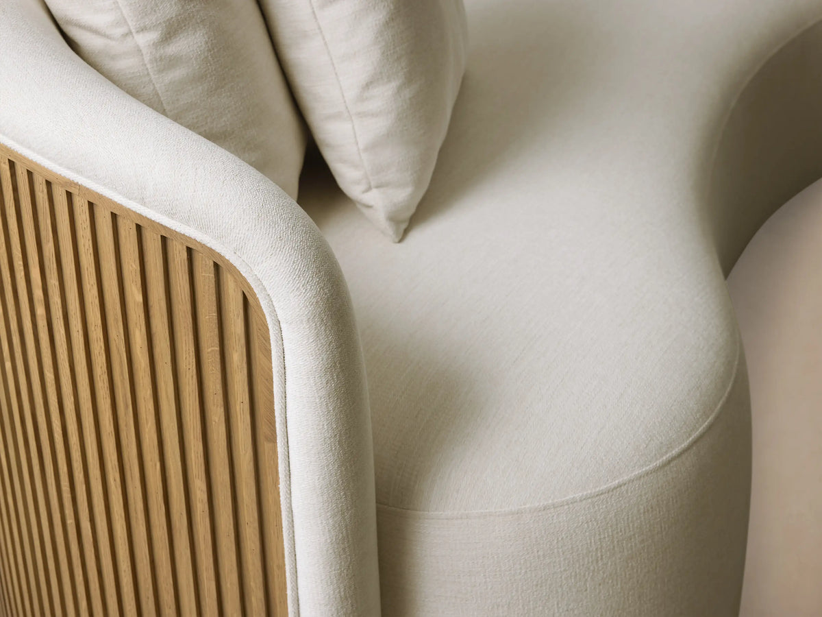 Close-up of the Finnley Daybed, showing white upholstered cushions, two toss pillows, and a slatted Honey wood back.