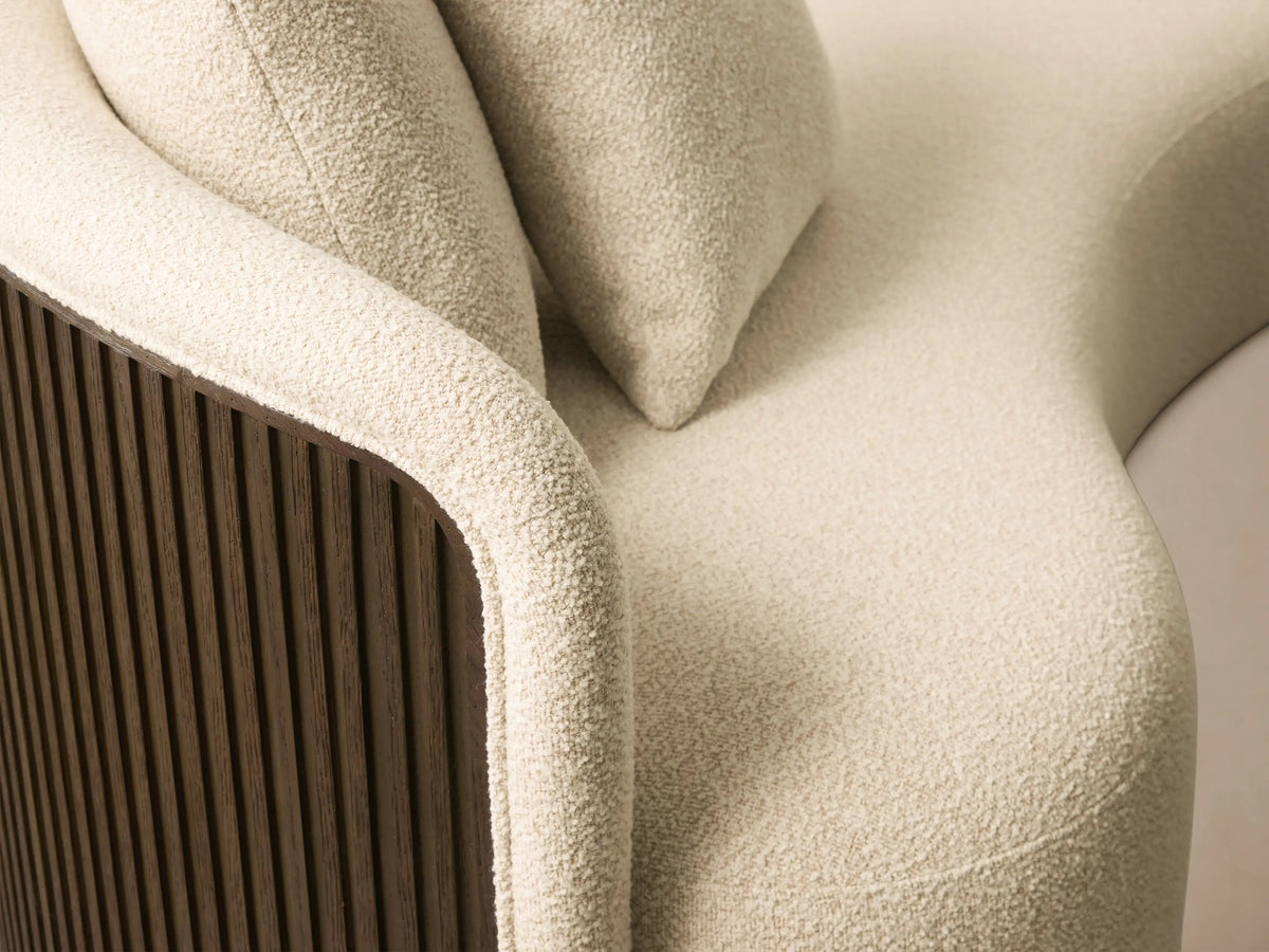 Front view of the Cream textured Finnley Daybed with a curved chaise design, two matching pillows, and a golden base.