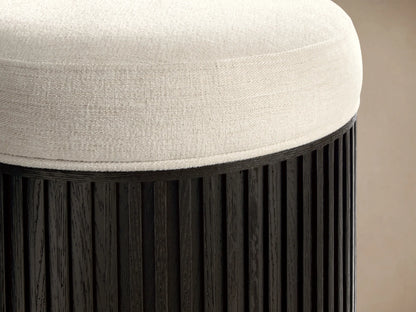 Close-up of the off-white textured cushion and Ebony ribbed wood base of the Finnley Ottoman.