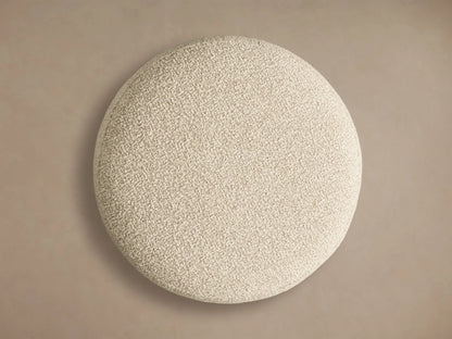 Close-up of the textured cream bouclé cushion and honey wood fluted base of the Finnley Ottoman.