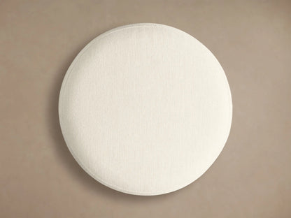 Front view of the Finnley Ottoman with a round off-white cushion, Honey-finished white oak slatted base, and gold bottom.