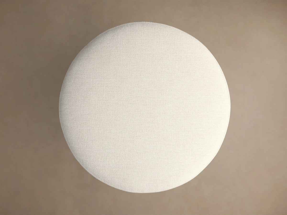 Close-up of the Finnley Ottoman, with an off-white textured fabric cushion and dark reeded wood base.