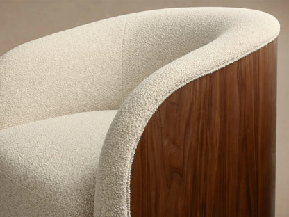 Front view of a cream-colored, curved armchair with a rounded back and arms, upholstered in a textured bouclv© fabric.