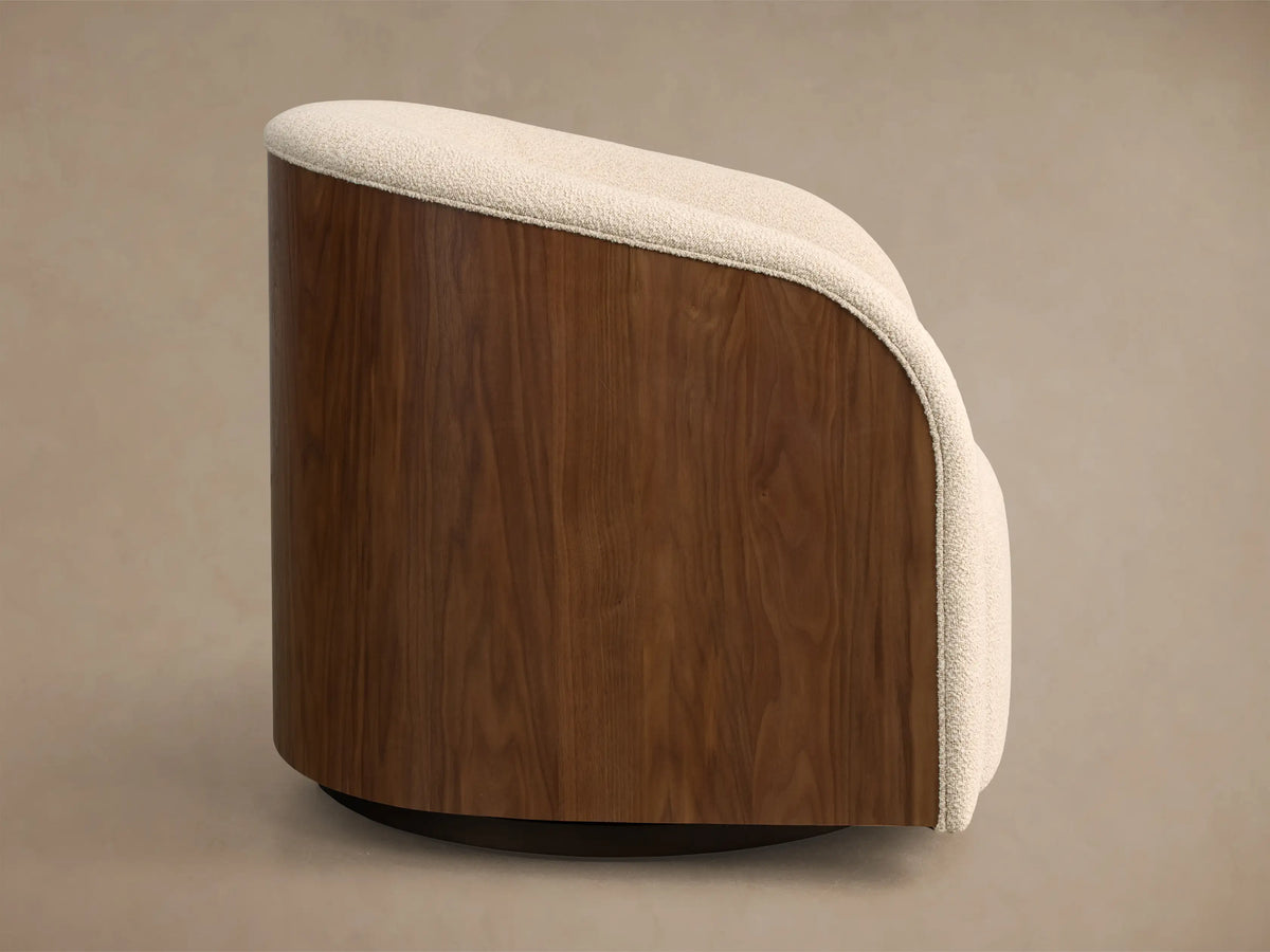 Side view of a Curved Wooden Armchair, showing its dark brown wood back, cream textured fabric top, and dark circular base.
