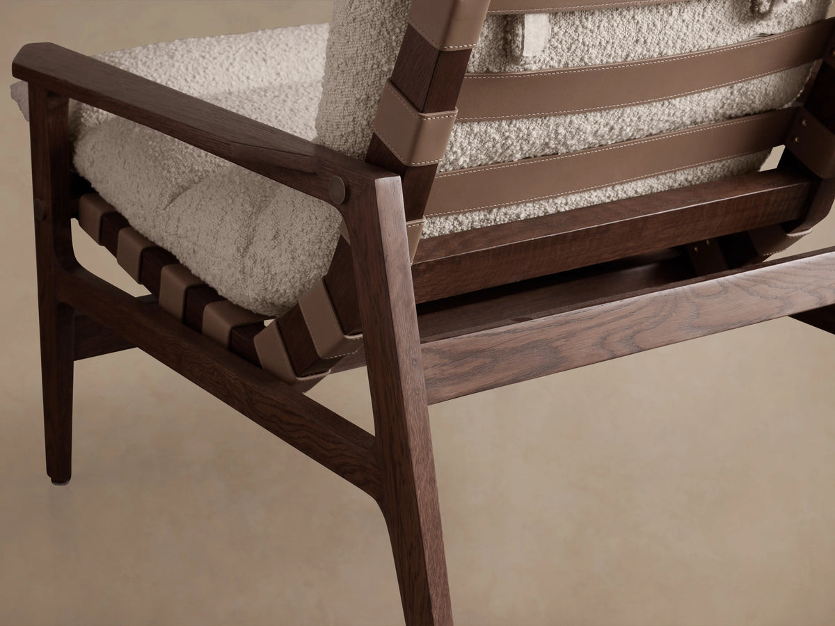 Rourke Chair with solid wood frame and hand-stitched leather straps. Sand-colored bouclé cushion on seat and back.