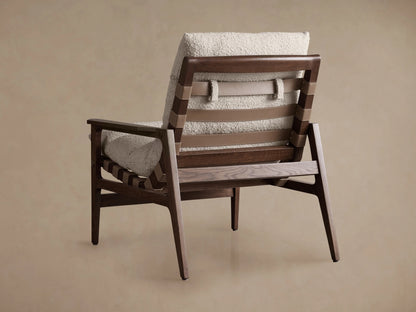 Rourke Chair with a slingback design, featuring solid wooden frame, hand-stitched leather straps, and sand-toned bouclé cushions.