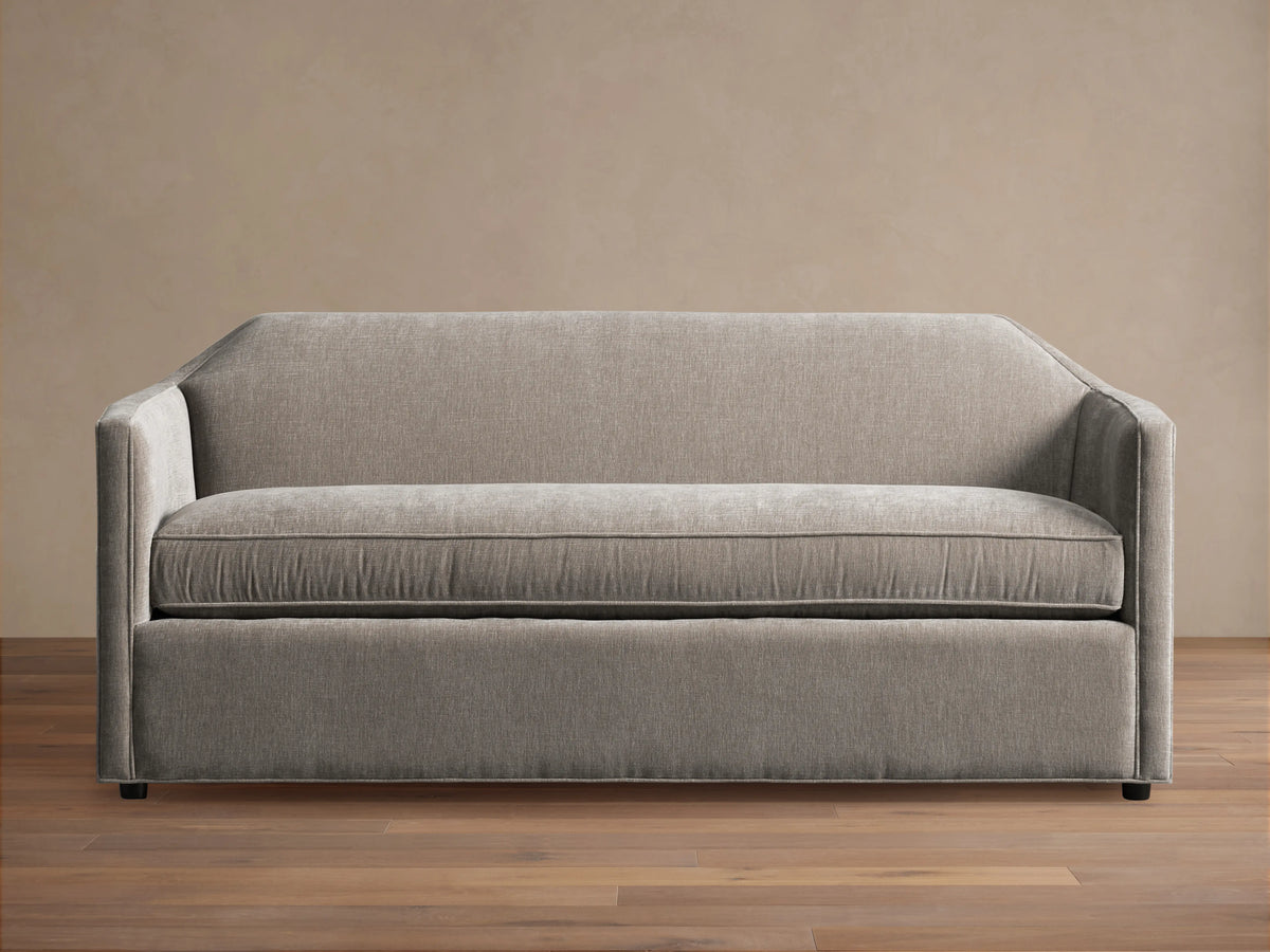 Grey Marina Sofa with a sleek, modern design featuring straight arms and a plush seat cushion. Sits on a hardwood floor with a neutral background.