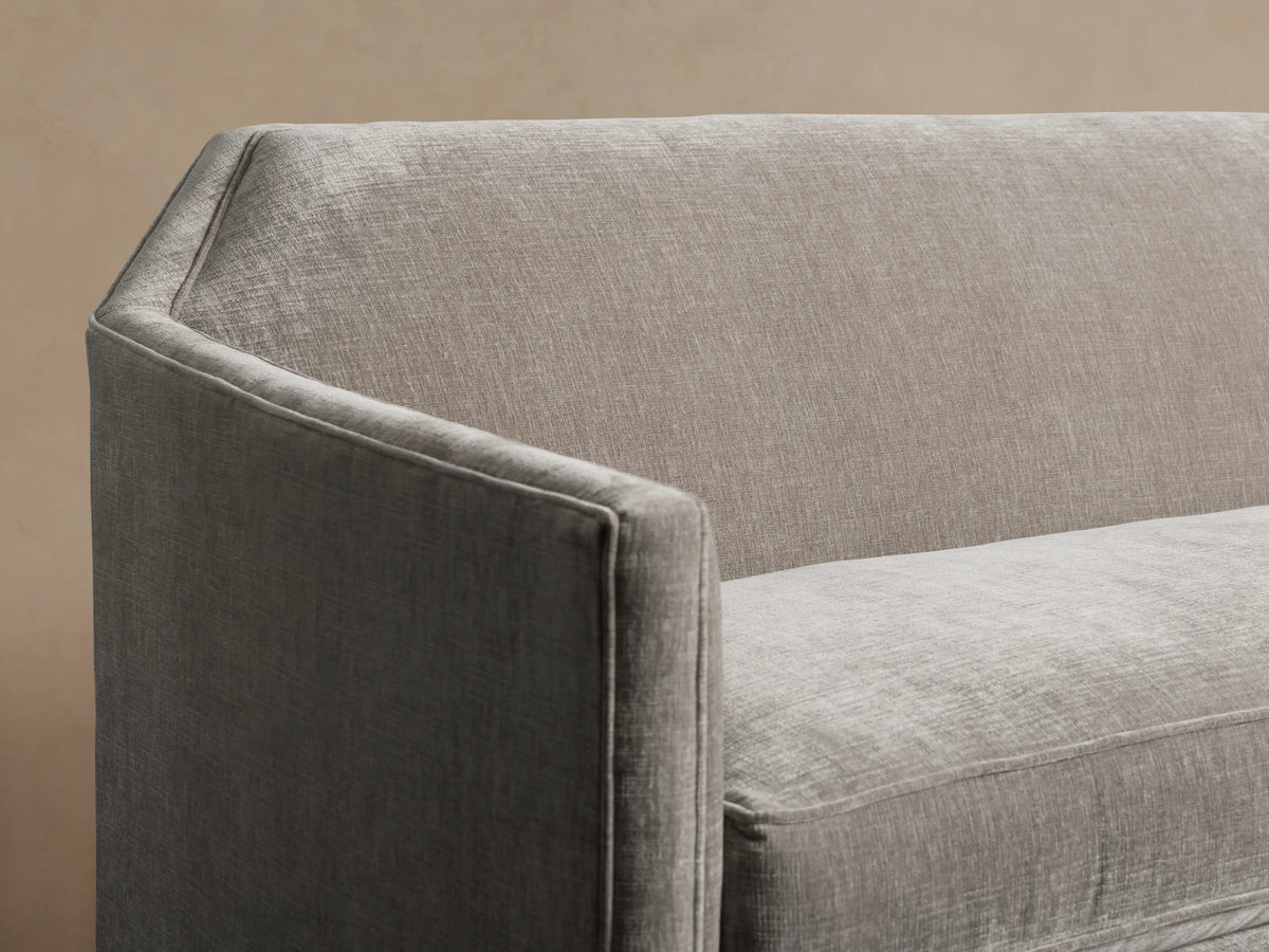 Gray Marina Sofa with a modern, angular design. Features smooth upholstery, a single seat cushion, and a slightly reclined backrest on a wooden floor.