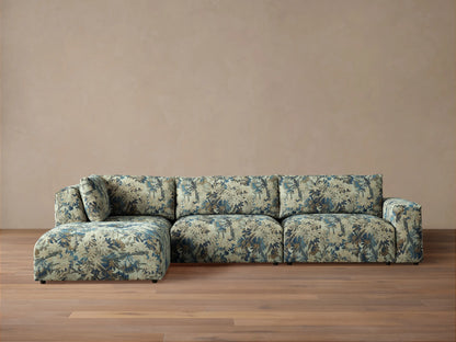 Keegan Four Piece Sectional with Ottoman, L-shaped, upholstered in light beige, blue, and brown tropical leaf pattern.