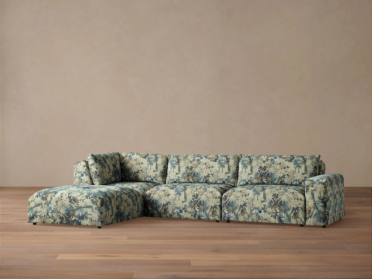 Keegan Four Piece Sectional with Ottoman, L-shaped, upholstered in light beige, blue, and brown tropical leaf pattern.