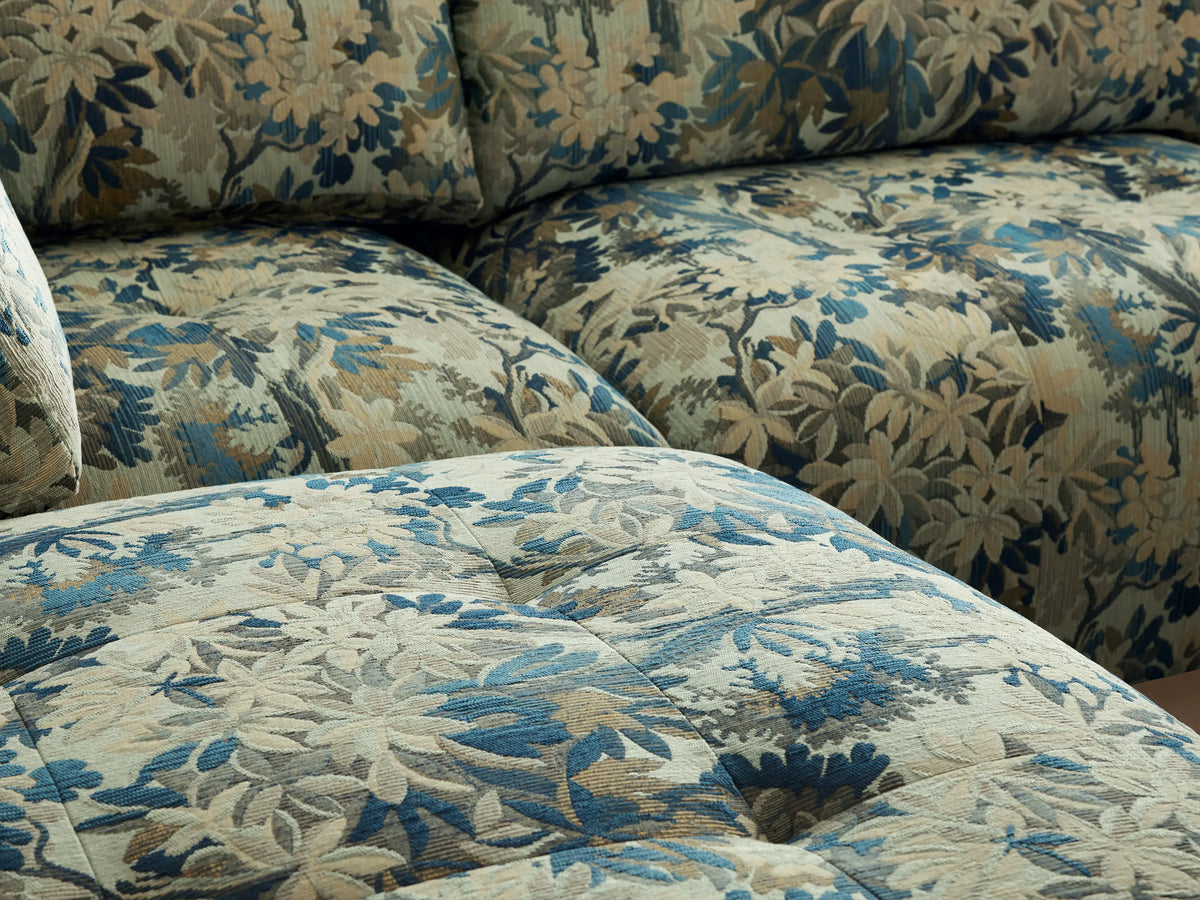 Keegan Four Piece Sectional, L-shaped with ottoman, blue/green/brown botanical print fabric on a wood floor.