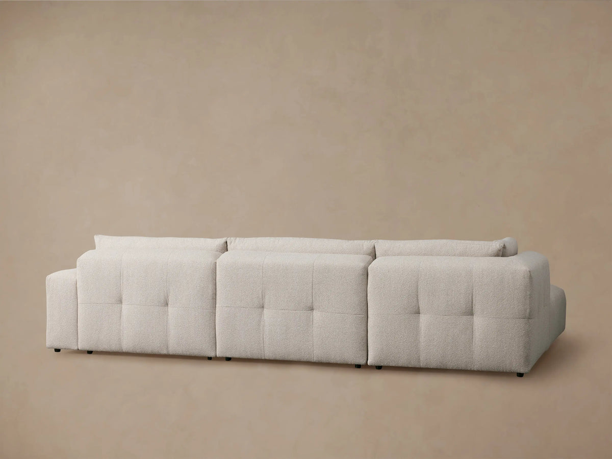 Close-up of Keegan Sectional's textured light beige fabric, showing the backrest and a plump cushion's seam.