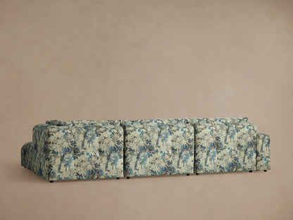 Keegan Four Piece Sectional fabric close-up. Blue, brown, and beige leafy pattern on textured cushions with subtle tufting.