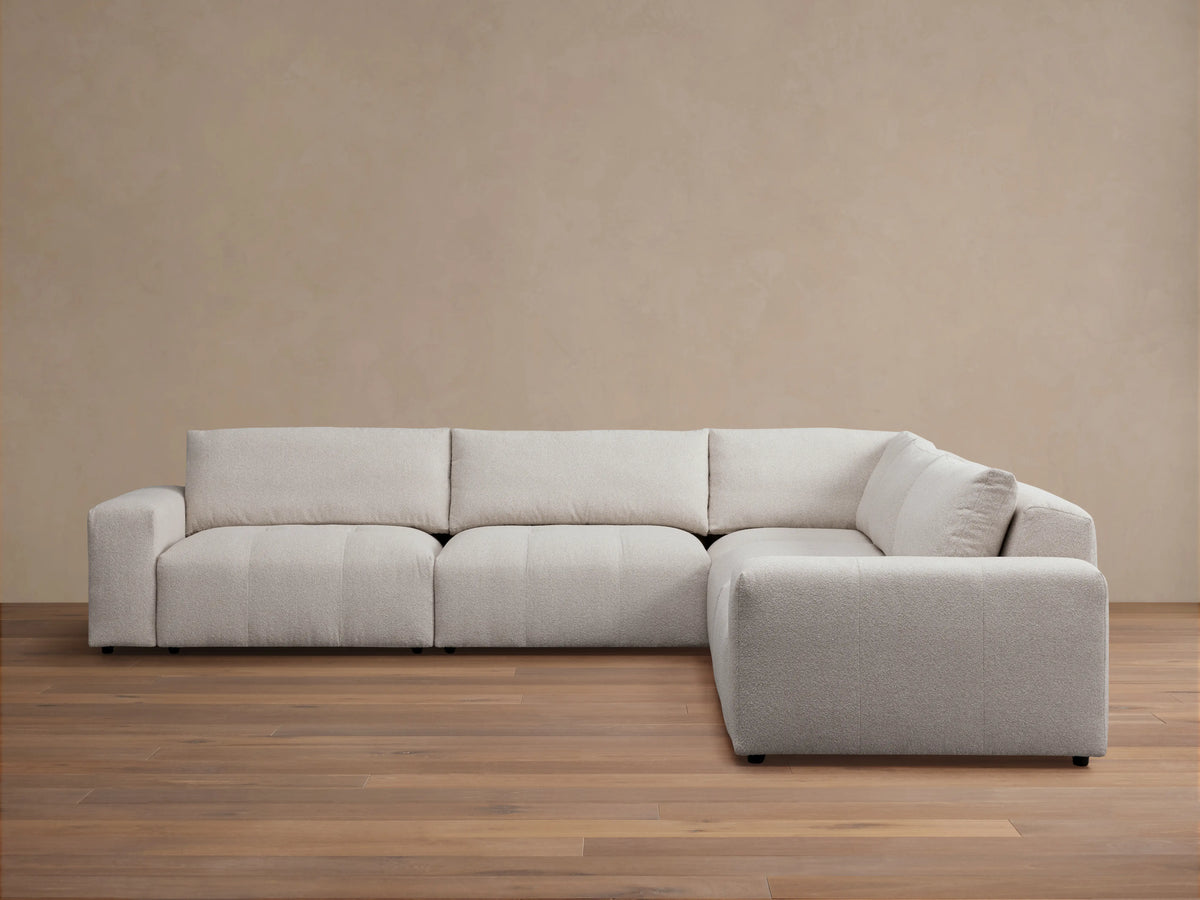 Keegan Five-Piece Corner Sectional in light gray fabric, featuring a modern design with plush seat and back cushions, set on a wooden floor.