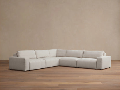 Keegan Five-Piece Corner Sectional in light gray fabric, featuring a modern design with plush seat and back cushions, set on a wooden floor.