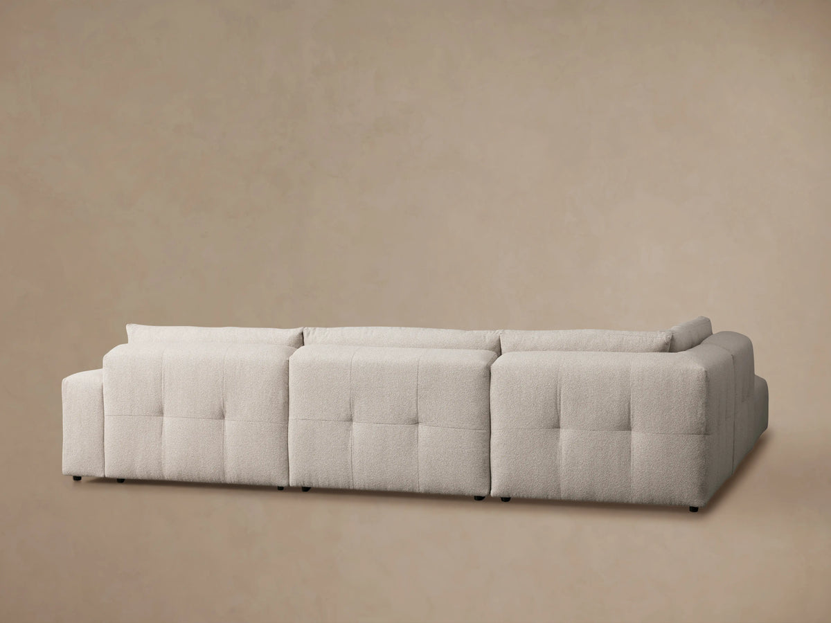 Close-up of the Keegan Five-Piece Sectional's textured beige fabric and cushioned backrest, showing detailed stitching.