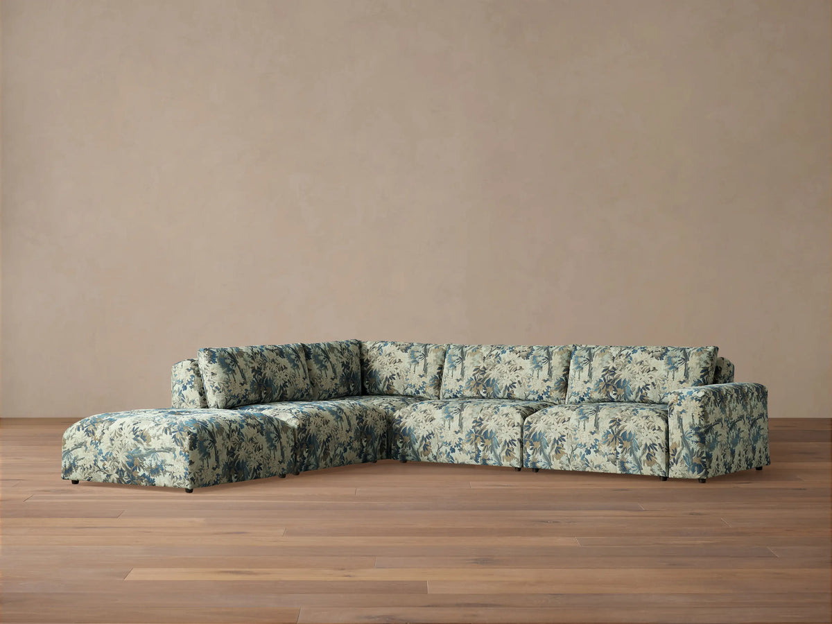 Front view of the Keegan Five-Piece Sectional in blue and cream botanical pattern, in a bright living room with armchairs.