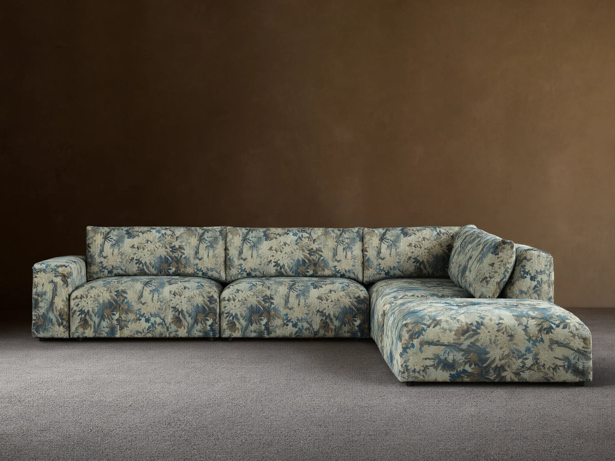 Keegan Five-Piece Sectional in L-shape, upholstered in blue, green, and brown leafy pattern, against a beige wall on a wood floor.