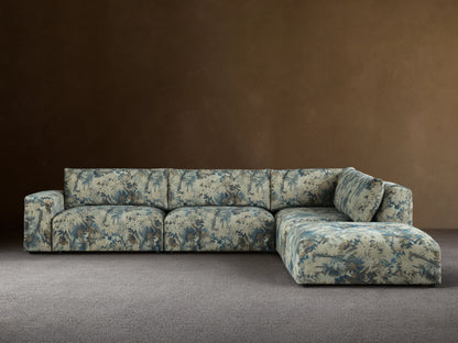 Keegan Five-Piece Sectional in L-shape, upholstered in blue, green, and brown leafy pattern, against a beige wall on a wood floor.