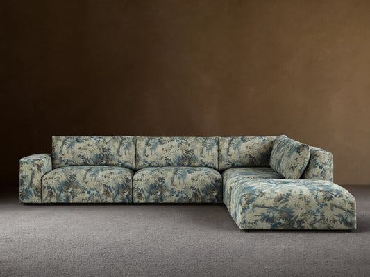 Keegan Five-Piece Sectional in L-shape, upholstered in blue, green, and brown leafy pattern, against a beige wall on a wood floor.