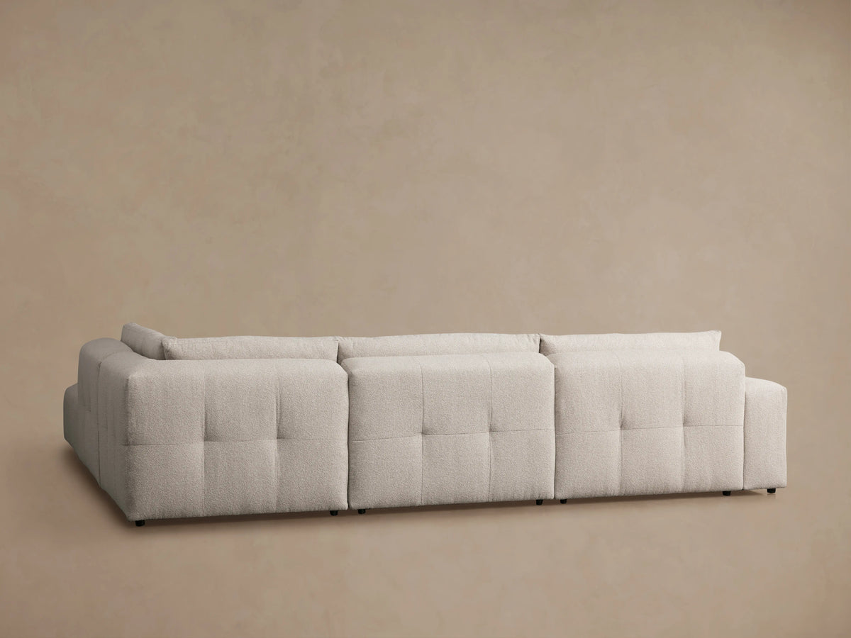 Keegan Five-Piece Sectional with textured beige fabric, showing a close-up of its tufted backrest and cushion seams.