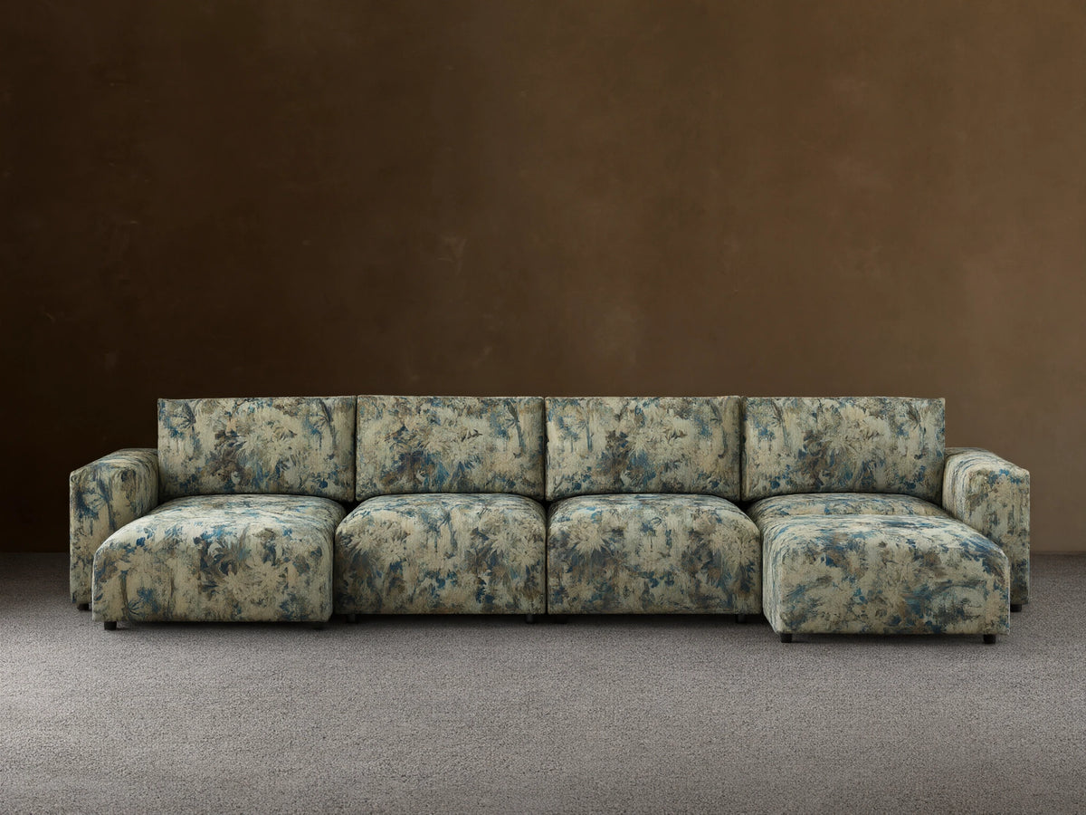 Keegan Six-Piece Sectional in light green fabric with blue tropical leaf pattern, U-shaped, on wood floor against tan wall.