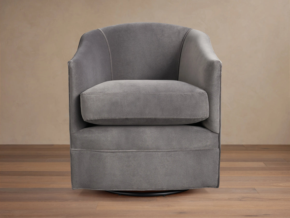 Giles Swivel Chair in dark gray fabric, featuring a curved backrest and wide seat cushion on a round base for 360-degree rotation.