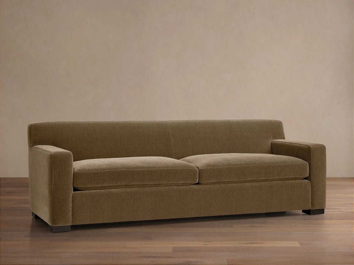 Bronte Sofa: Modern, muted olive green fabric sofa with straight lines, square arms, and dark feet on a wood floor.