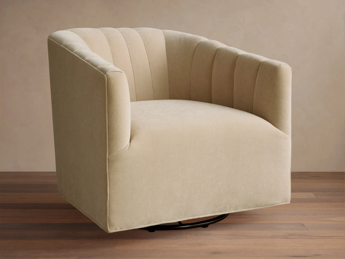 Light cream Ellison Channel-Stitched Swivel Chair, front-right view. Channel stitching on back, black swivel base on wood floor.