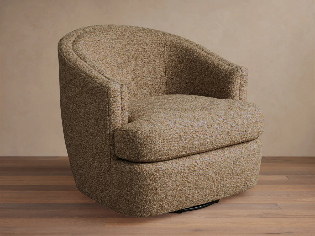 Kieran Swivel Chair with a curved backrest and cushioned seat in a textured beige fabric, placed on a wooden floor.