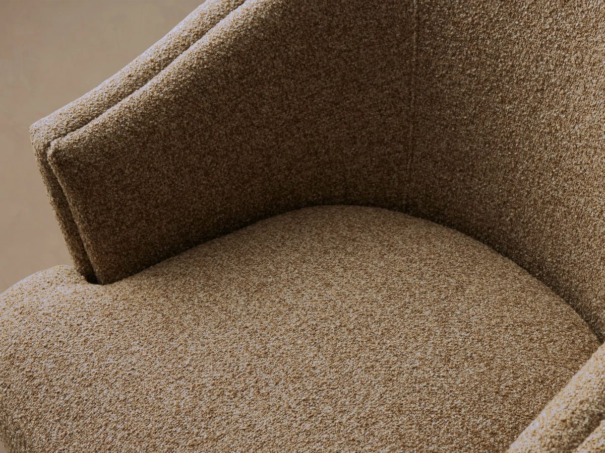 Kieran Swivel Chair in brown fabric, featuring a rounded backrest and cushioned seat, set on a wooden floor.