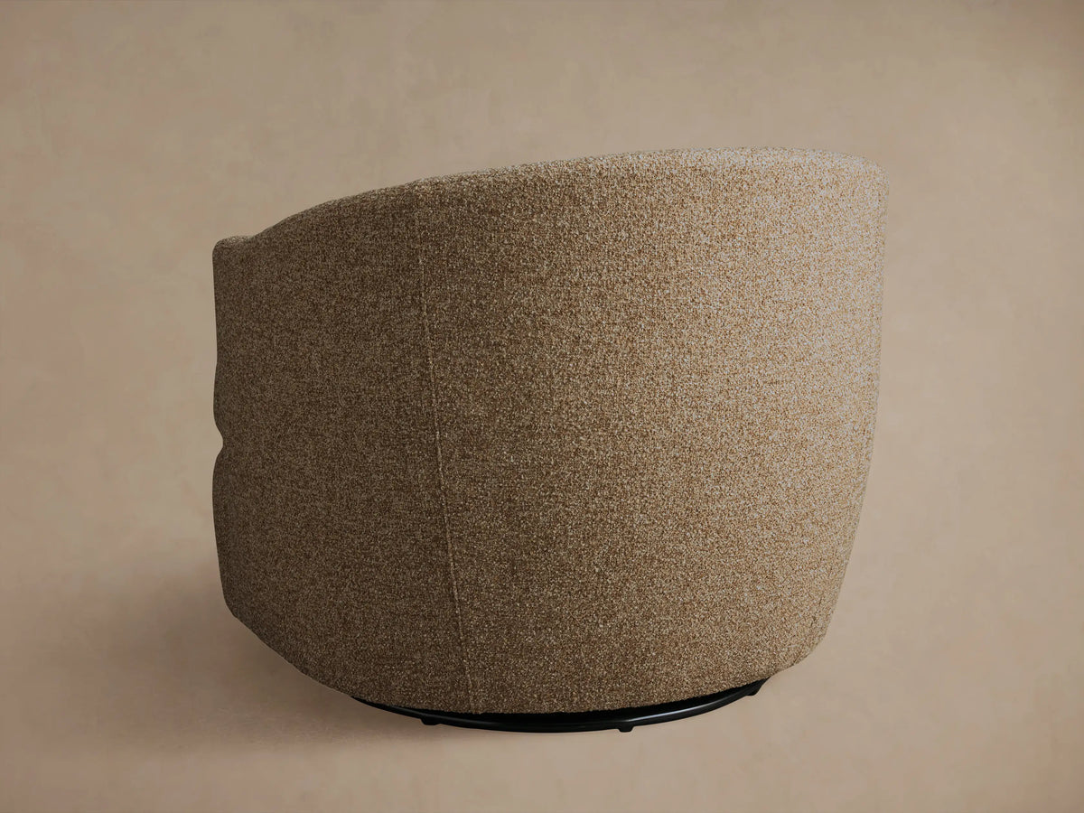 Kieran Swivel Chair in beige textured fabric, shown from a side angle, featuring a rounded back and cushioned seat on a swivel base.
