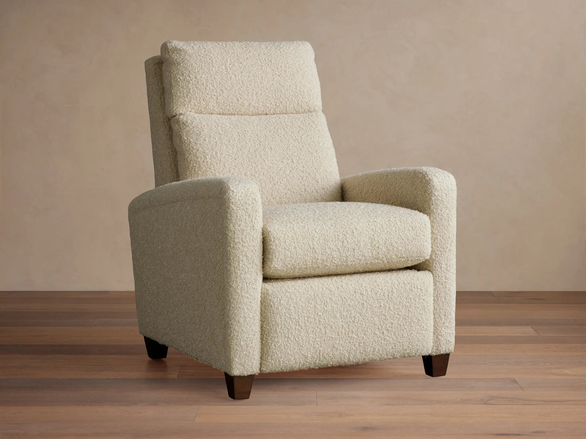 Cream Colfax Motion Recliner in textured fabric, facing forward. Dark wooden legs on a wood floor, light background wall.
