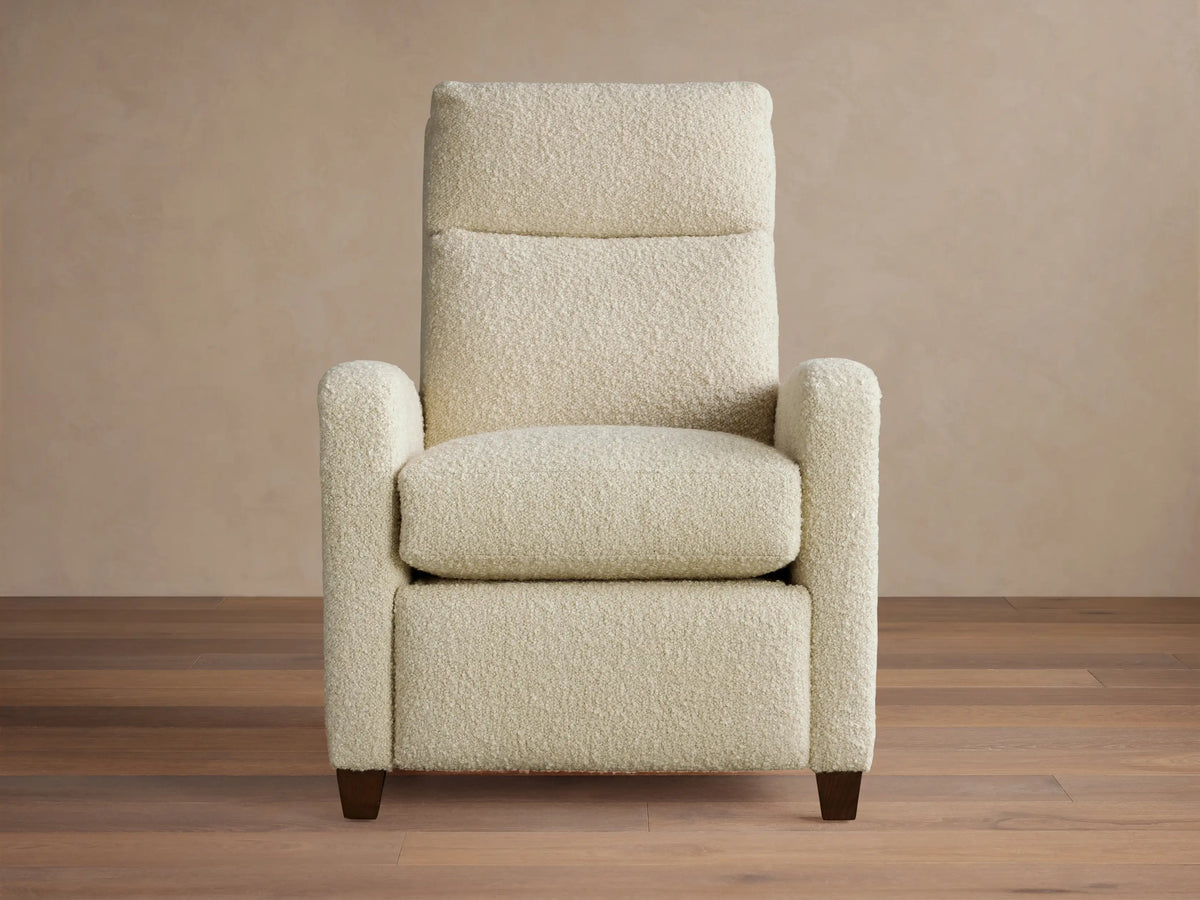 Cream Colfax Motion Recliner in textured fabric, facing forward. Dark wooden legs on a wood floor, light background wall.