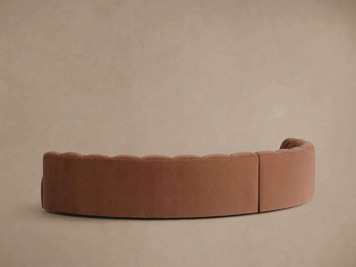Close-up of the terra cotta velvet Amira Two-Piece Curved Sectional, showing the fluted backrest and curved seat.