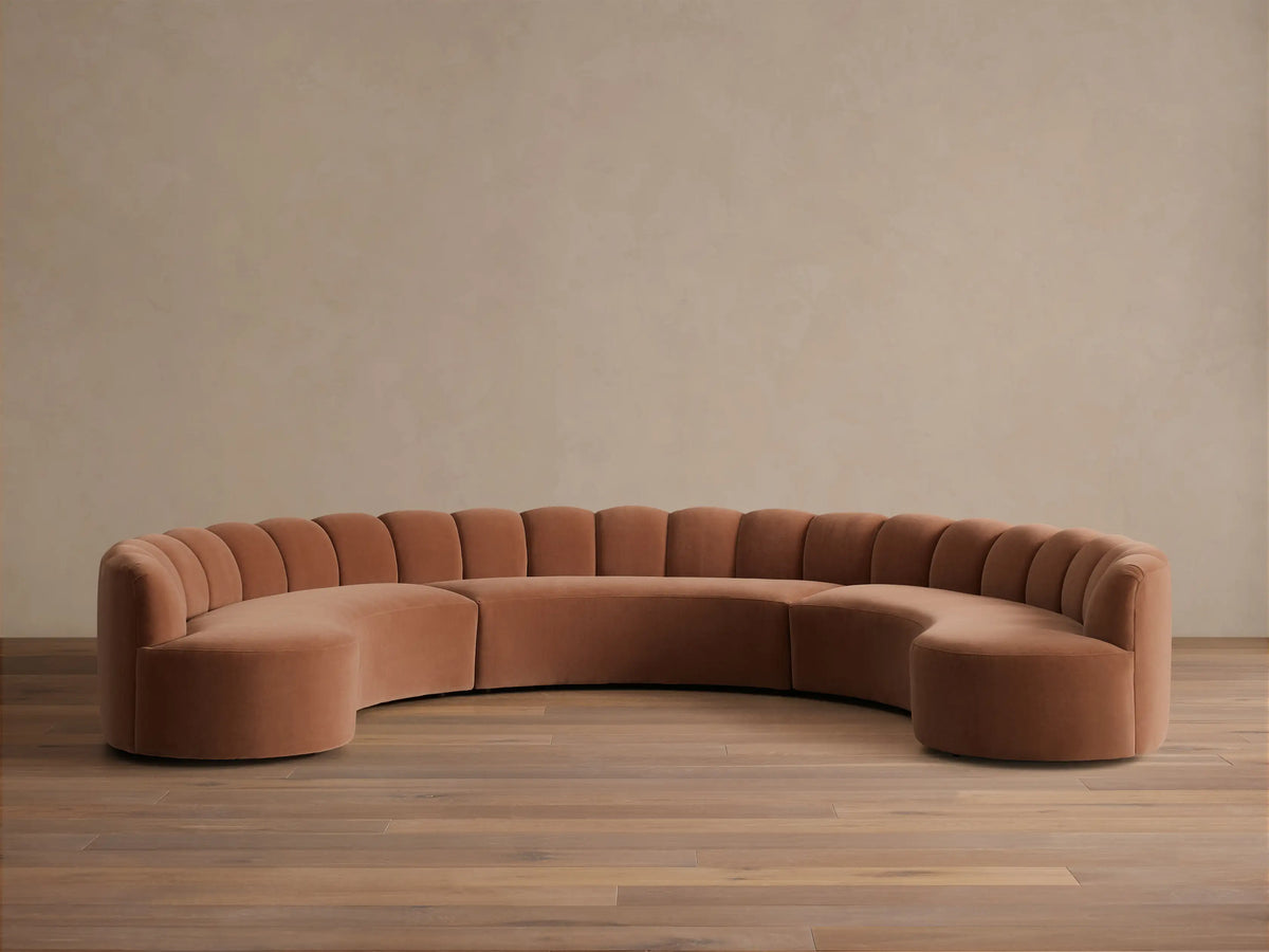 Front view of a Rust Amira Three-Piece Curved Sectional with a channeled backrest.