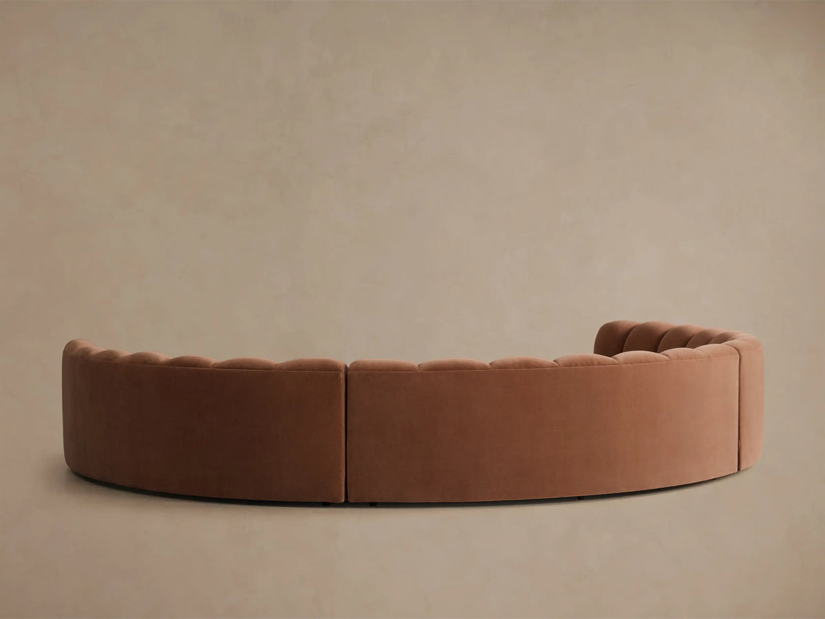 Rear view of the Rust Amira Three-Piece Curved Sectional, featuring channel tufting on the backrests.