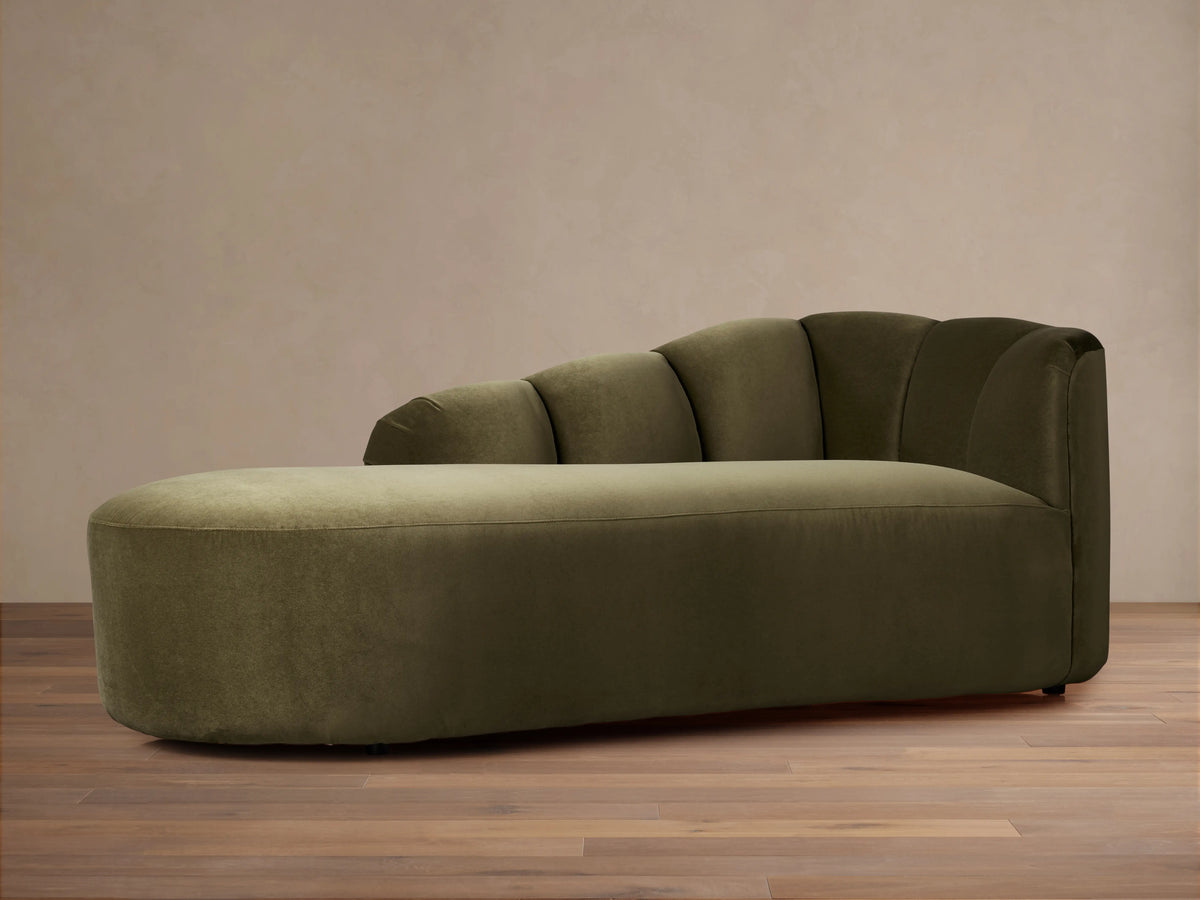 Amira Daybed, soft olive green velvet, with an elegantly curved backrest, shown from a side view against a plain background.