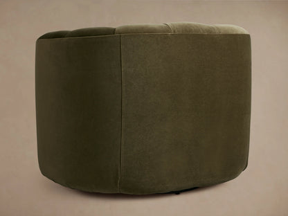 Front view of Amira Swivel Chair, dark olive green velvet with channel tufted curved back, on wood floor.