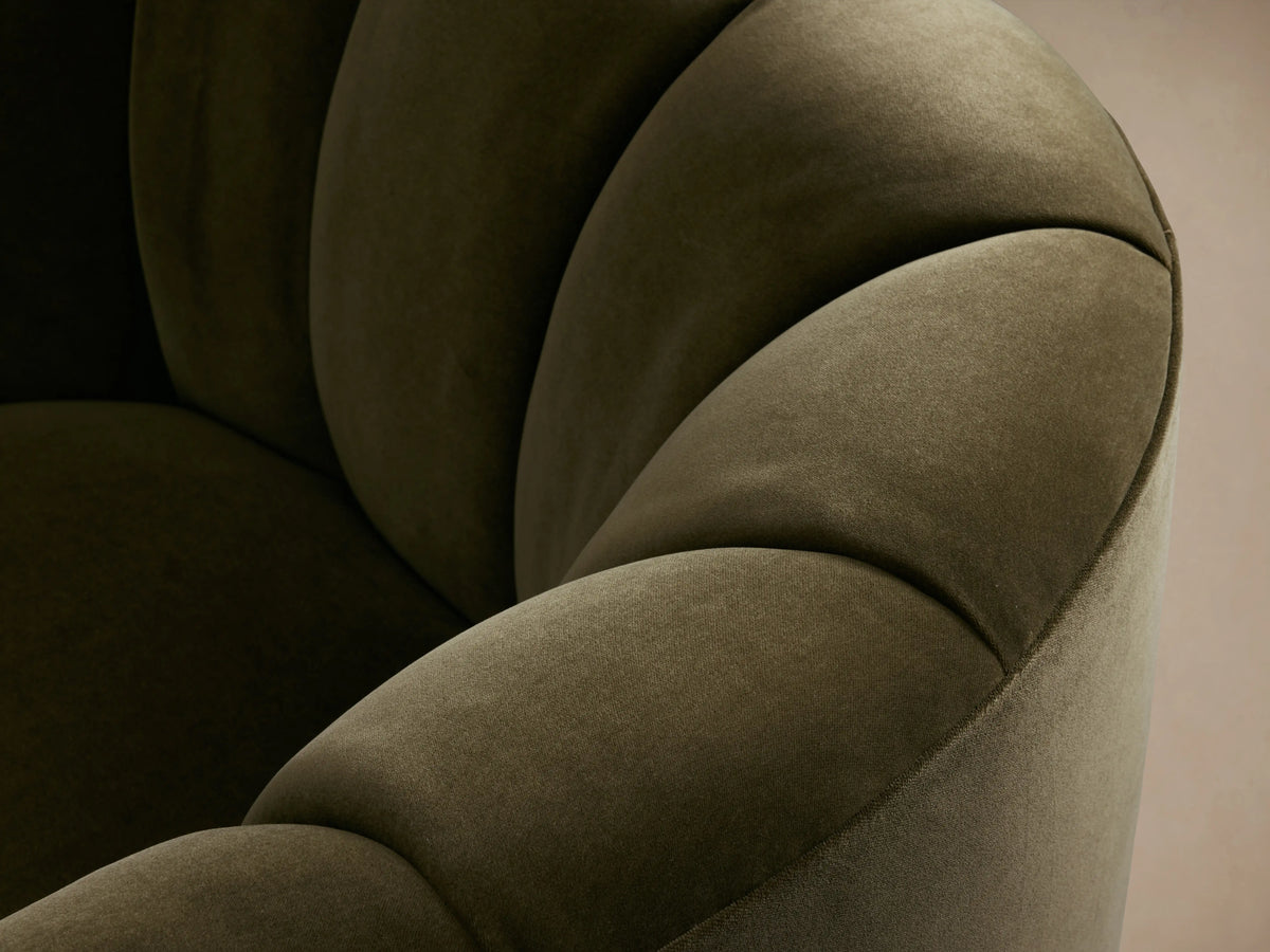 Dark olive green upholstered Amira Swivel Chair, viewed from the back and side. Features a curved form and tufted top edge.